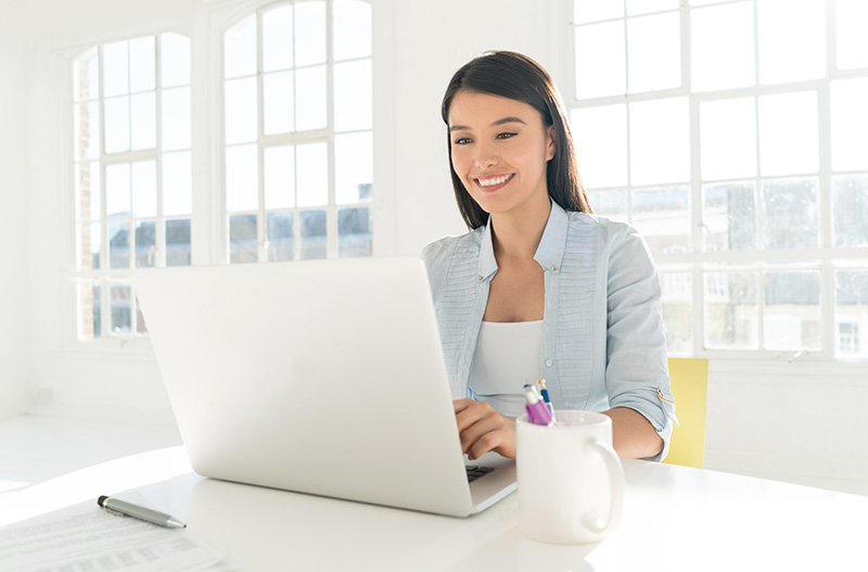 dame qui sourit en faisant sa facturation sur l'ordinateur